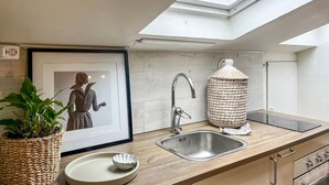A modern kitchen with a skylight, a stainless steel sink, a woven basket, and a framed artwork. - Cozy apartment in Borås with WiFi (Borås)