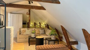 A cozy loft-style living room with a high ceiling, exposed wooden beams, a sofa set, a coffee table, and a small side table. - Cozy apartment in Borås with WiFi (Borås)