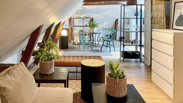 A cozy loft-style living space with a sofa, a round coffee table, and a dining area with chairs and a table. - Cozy apartment in Borås with WiFi (Borås)