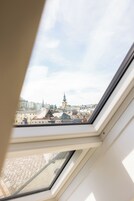 Un tragaluz con vistas a un paisaje urbano, incluyendo una aguja de iglesia destacada.