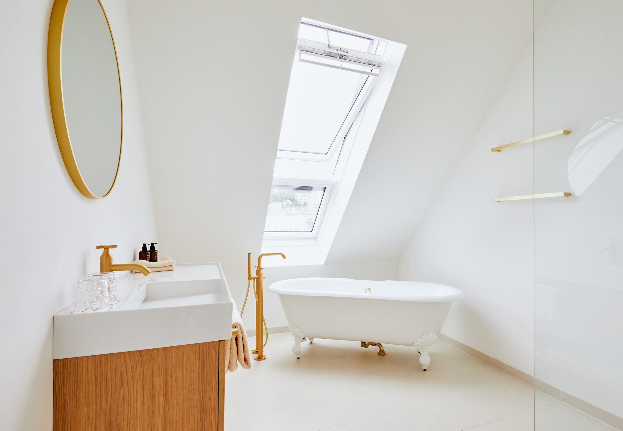 A modern bathroom with a freestanding bathtub, a large mirror, and a skylight.