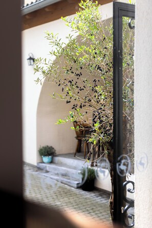 An outdoor area with a potted olive tree, a tiled patio, and a black metal gate. - Boutique Hotel Zum Goldenen Hirschen (Gmunden)