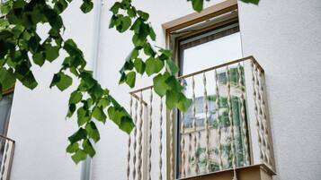 Une fenêtre dotée d’un garde-corps en métal torsadé original et offrant une vue sur la verdure environnante.