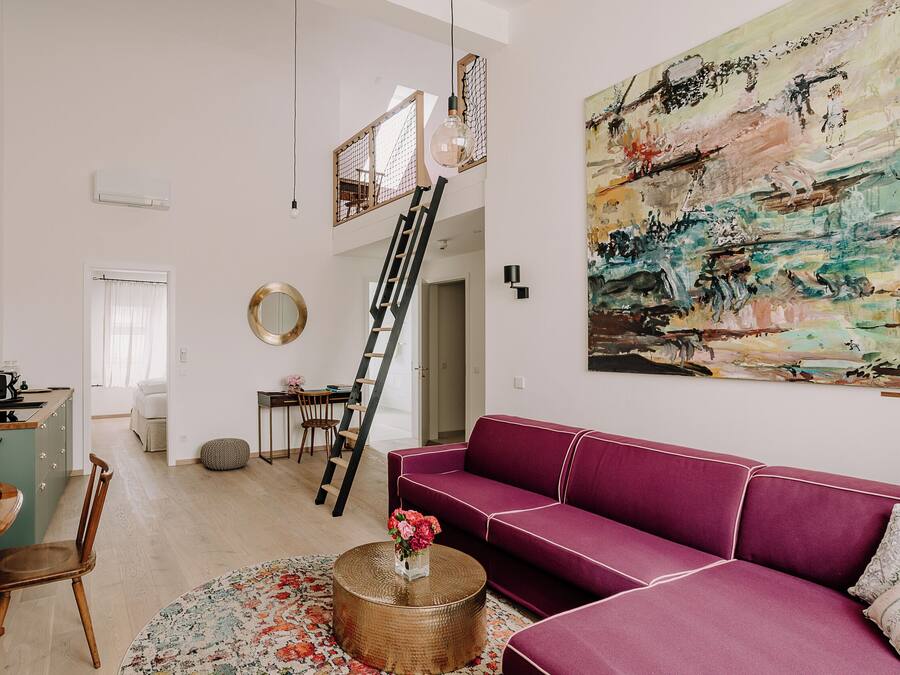 Una sala de estar moderna con un sofá púrpura, una mesa redonda de centro y un cuadro abstracto grande en la pared.