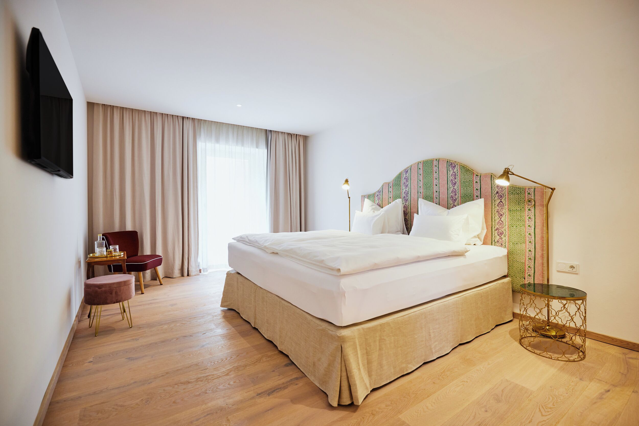 A hotel room with a large bed, a desk, and a chair.