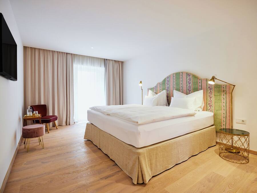 A hotel room with a large bed, a desk, and a chair.