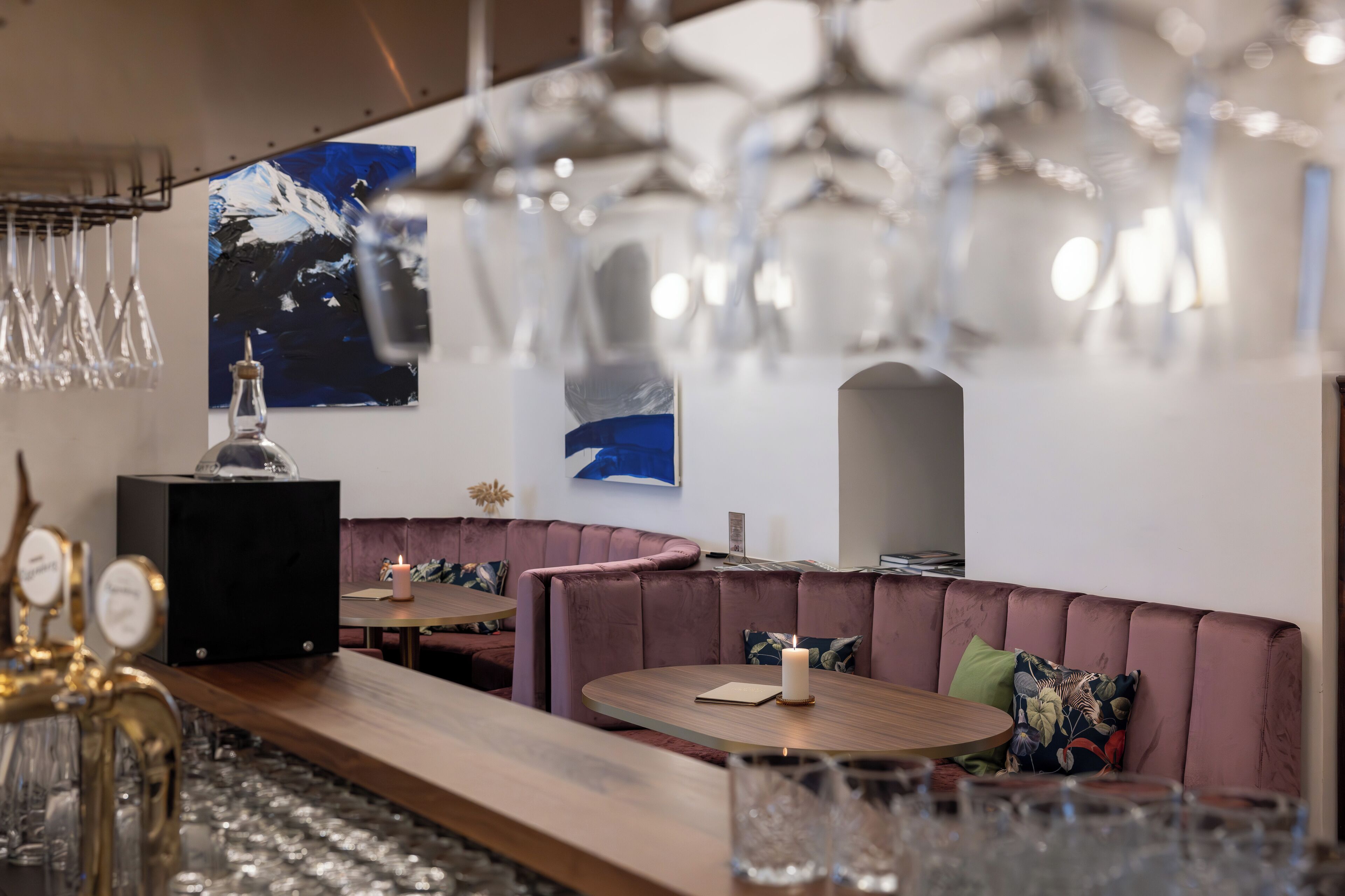 Zona de bar moderna con asientos, iluminación colgante y obras de arte en las paredes.