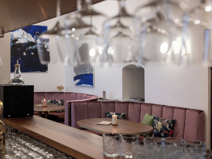Zona de bar moderna con asientos, iluminación colgante y obras de arte en las paredes.