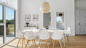 A modern dining room with a large table set for six, white chairs, and a hanging light fixture. - Stunning home in Jerup with sauna (Jerup)