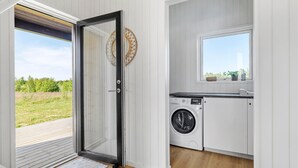 A laundry room with a washing machine, a small window with a view, and a door leading to an outdoor area. - Stunning home in Jerup with sauna (Jerup)