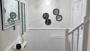 A narrow hallway with a white door, a radiator, and a small shelf with a decorative item.