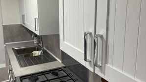 A kitchen with white cabinets, a stainless steel sink, and a gas stove.