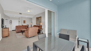 A spacious living room with a glass dining table, leather sofa, and a ceiling fan.