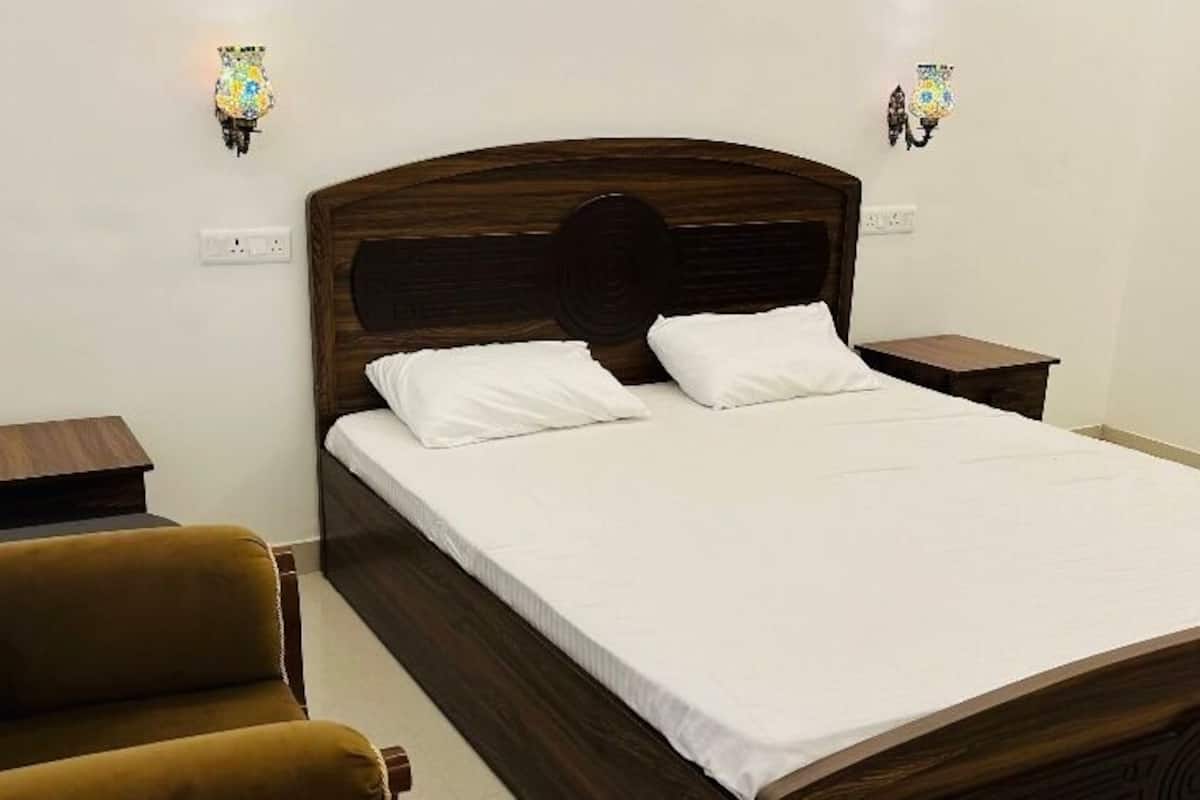 A neatly made bed with white linens, a wooden headboard, and two bedside tables with lamps.
