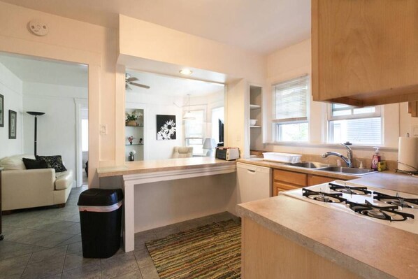 A modern kitchen with a gas stove, sink, and a dining area with a table and chairs.