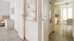 A room with a white door, a framed picture on the wall, a wooden chair, and a small table. - GuestHost - Cosy APT Porta Venezia & Buenos Aires! (Milano)