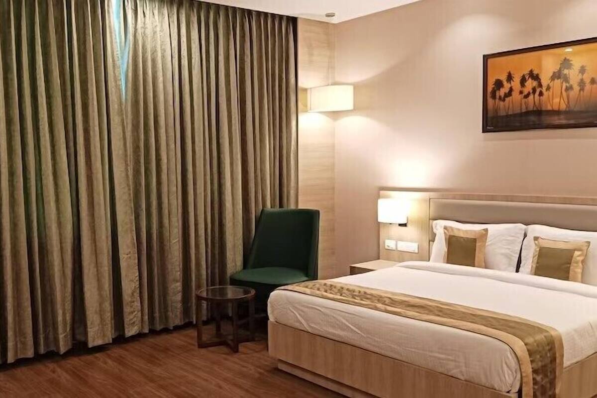 Habitación de hotel con una cama, una silla, una lámpara y un cuadro en la pared.