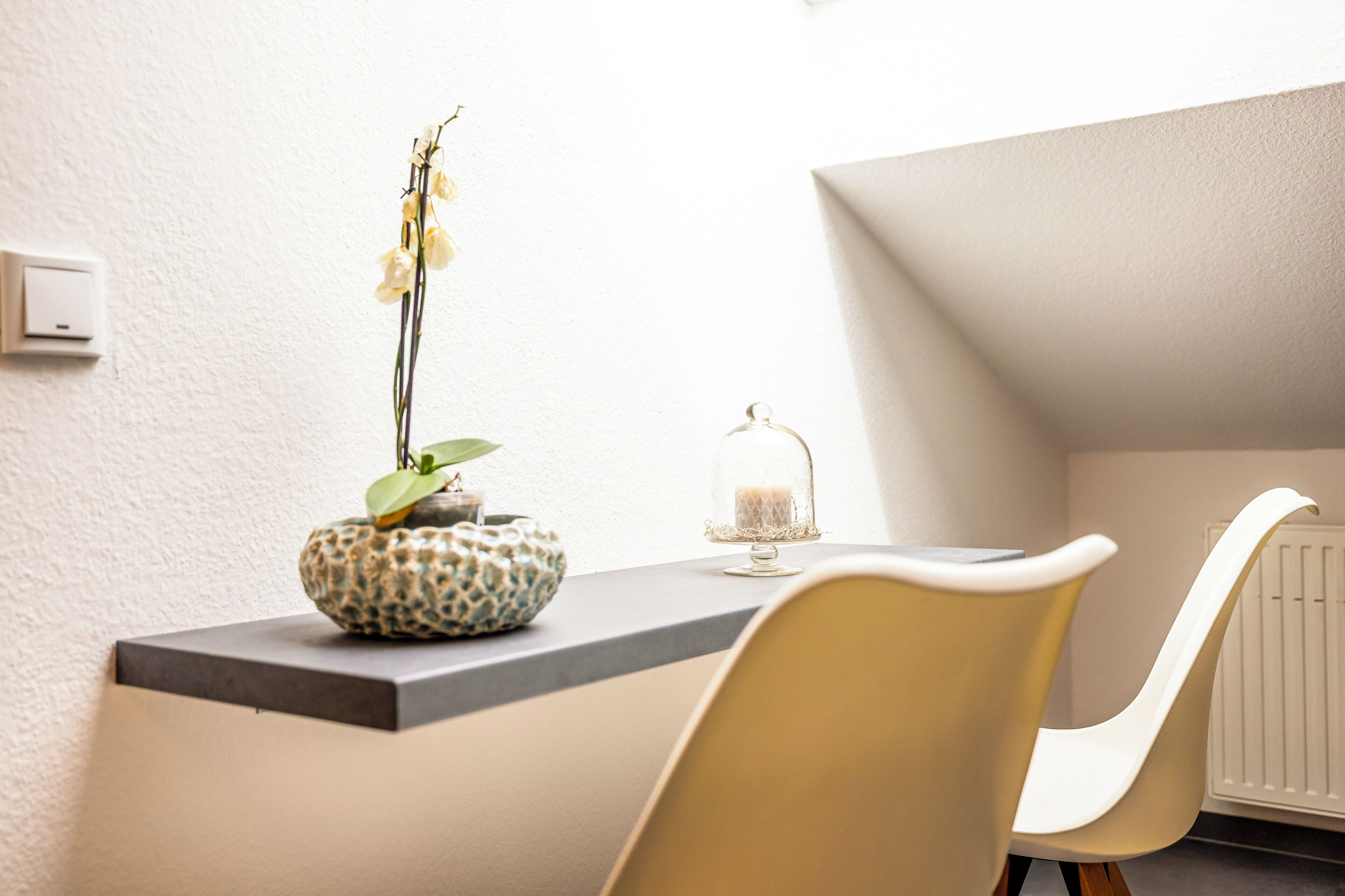 A modern room with a small table, a potted plant, and a decorative glass item.