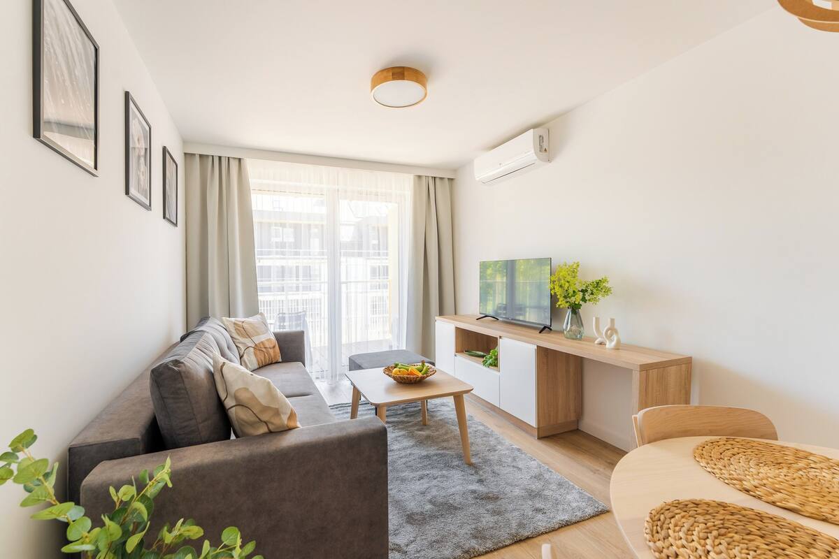 Un salon moderne comprenant un canapé, une table basse, un téléviseur et un petit coin repas.