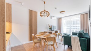 Un salon moderne avec un canapé vert, une table à manger en bois et un luminaire suspendu.