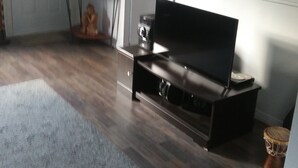 Ein Raum mit einem dunkelbraunen Ledersofa, einer weißen Tür, einem gerahmten Gemälde an der Wand und einer kleinen Statue auf einem Tisch.