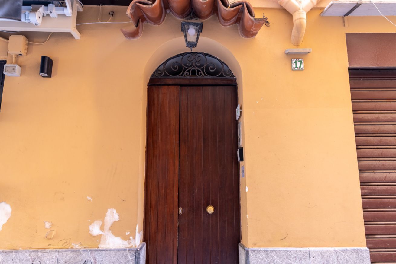 Una puerta de madera con un arco de metal, un pequeño accesorio de iluminación encima y el número '17' en la pared.