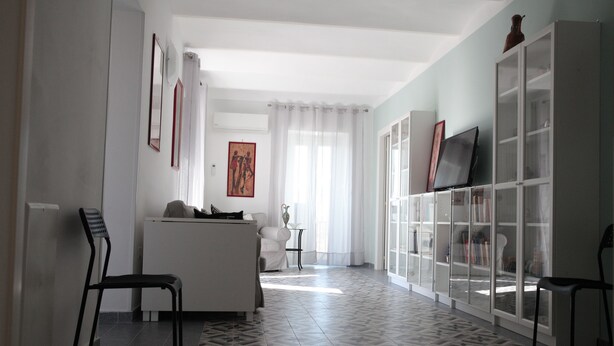 A modern living room with a sofa, chairs, a TV, and a bookshelf. - B&B Ex Albergo Centrale Atessa a place that has a history (Atessa)