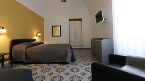 A bedroom with a bed, bedside table, dresser, and a television mounted on the wall. - B&B Ex Albergo Centrale Atessa a place that has a history (Atessa)