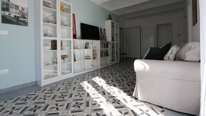 A living room with a patterned floor, a white sofa, and a cabinet with various items. - B&B Ex Albergo Centrale Atessa a place that has a history (Atessa)