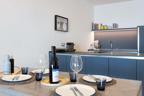Cozinha moderna com área de jantar para dois, com uma garrafa de vinho, copos e máquina de café.