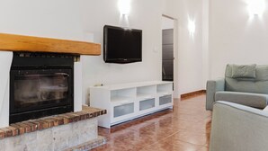 Ein Wohnzimmer mit Kamin, einem flachbildfernseher darüber und einer weißen Unterhaltungseinheit, sowie einem grauen Sofa.
