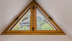 Ein dreieckiges Fenster mit Blick auf Gebäude und Bäume.