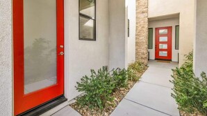 A modern building with a red door, a small window, and a stone accent wall. - The Desert Oasis Casita (Palm Desert)