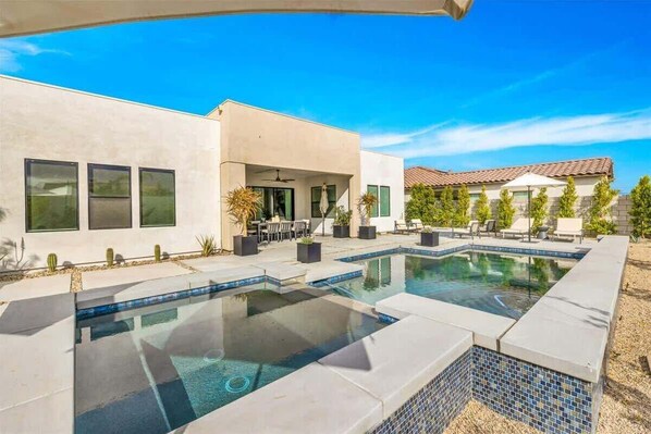 Une maison moderne dotée d’une piscine, de mobilier de jardin et d’un espace extérieur couvert.