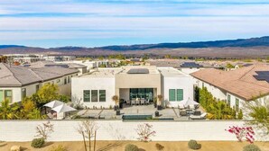 A residential area with modern houses, a swimming pool, and a clear view of distant mountains. - The Desert Oasis Casita (Palm Desert)