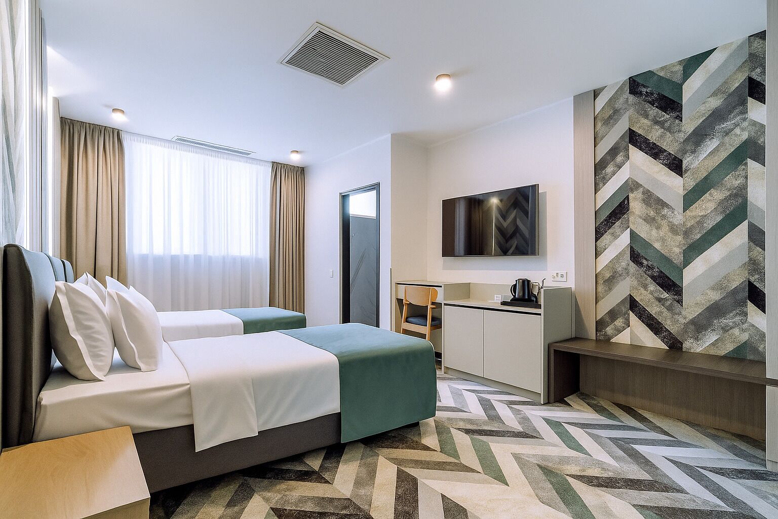 Ein Hotelzimmer mit Bett, Schreibtisch, Stuhl und Fernseher.
