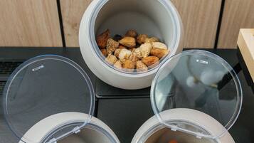 Three containers with lids, one containing dried apricots, another with walnuts, and the third with dried plums.