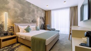 Habitación de hotel con una cama grande, un escritorio, una silla, un televisor y una pared con un mural texturizado.