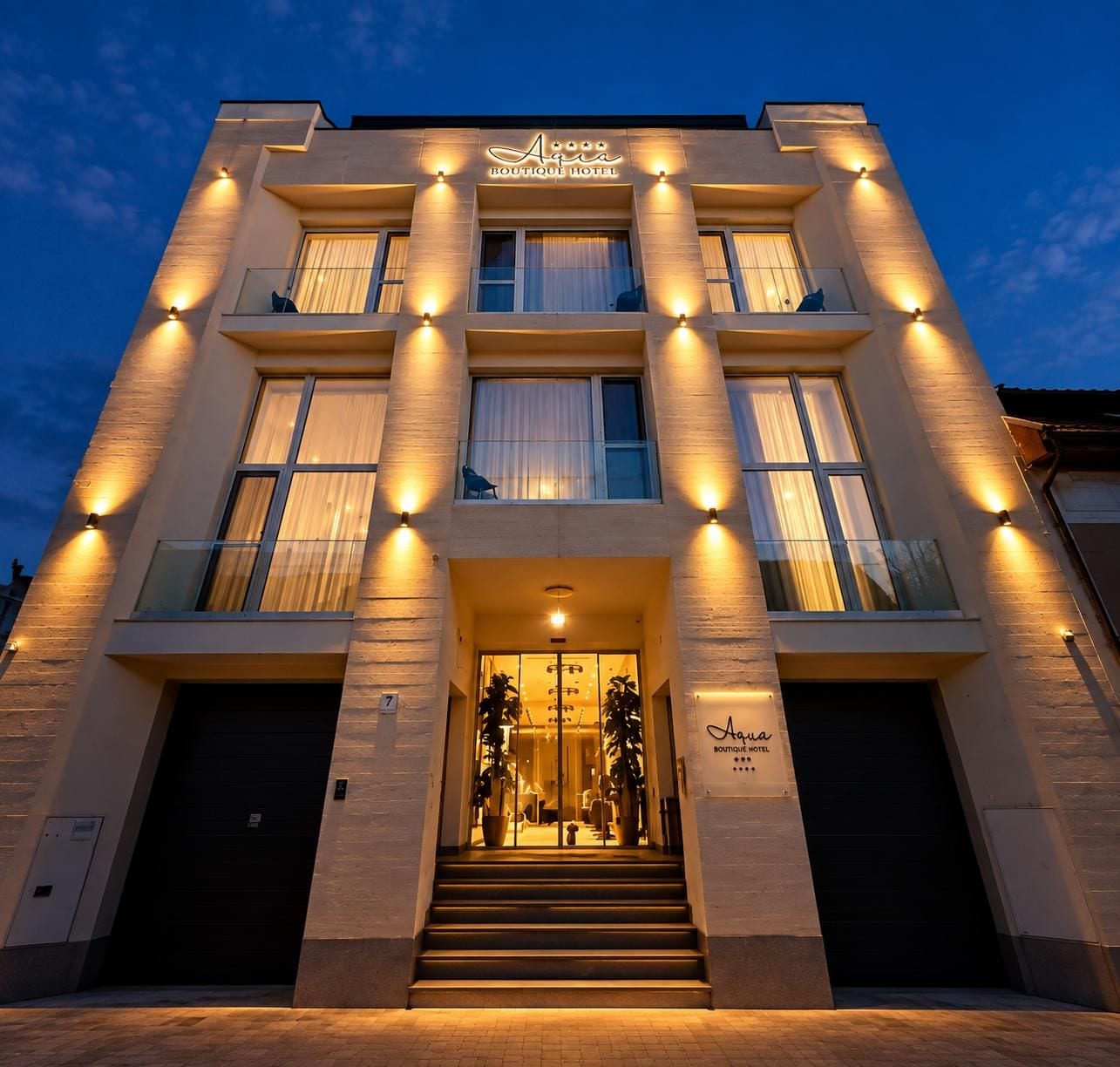 A multi-story boutique hotel with a modern facade, illuminated exterior lighting, and a grand entrance with a staircase.