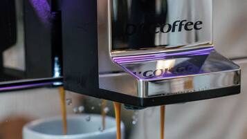 Een koffieapparaat schenkt koffie in twee witte kopjes.