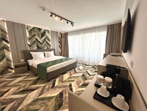 Une chambre d’hôtel avec un lit, un bureau doté d’une machine à café et un téléviseur.
