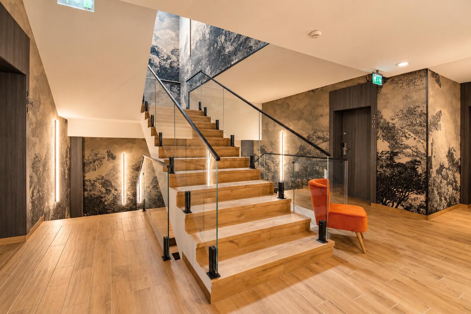 Un interior moderno con una escalera de madera, barandales de vidrio y una silla roja.