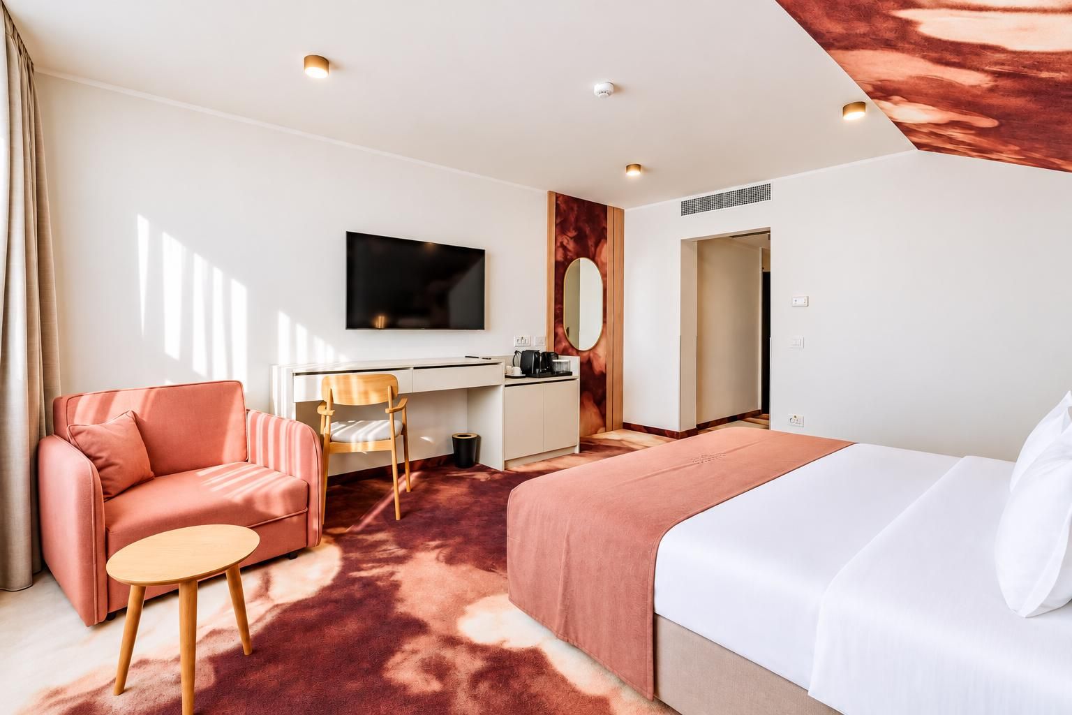 A hotel room with a bed, a sofa, a desk, and a TV.