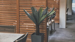 A restaurant interior with wooden partitions, tables, chairs, and a potted plant. - The Walk-Up Waikiki Beach  (Honolulu)