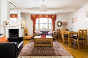 Una sala de estar con chimenea, un sofá, una mesa de centro y un comedor con sillas y una mesa.