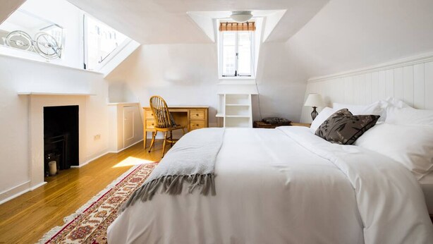 A bedroom with a large bed, a desk, a chair, and a skylight.