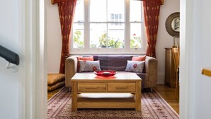 A cozy room with a sofa, a wooden coffee table, and a window with curtains.