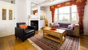 A living room with a black leather sofa, a wooden coffee table, and a patterned rug.