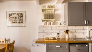 A compact kitchen with a wooden countertop, a dishwasher, and grey cabinets.