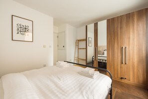 Ein Schlafzimmer mit Bett, Kleiderschrank, Spiegel und einem gerahmten Kunstwerk an der Wand.